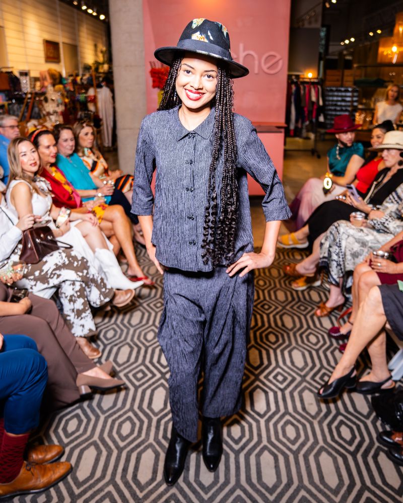 model in a matching grey stripe outfit and hat on a runway