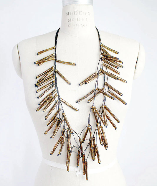 Necklace with gold and black fabric beads on a mannequin bust against a white background