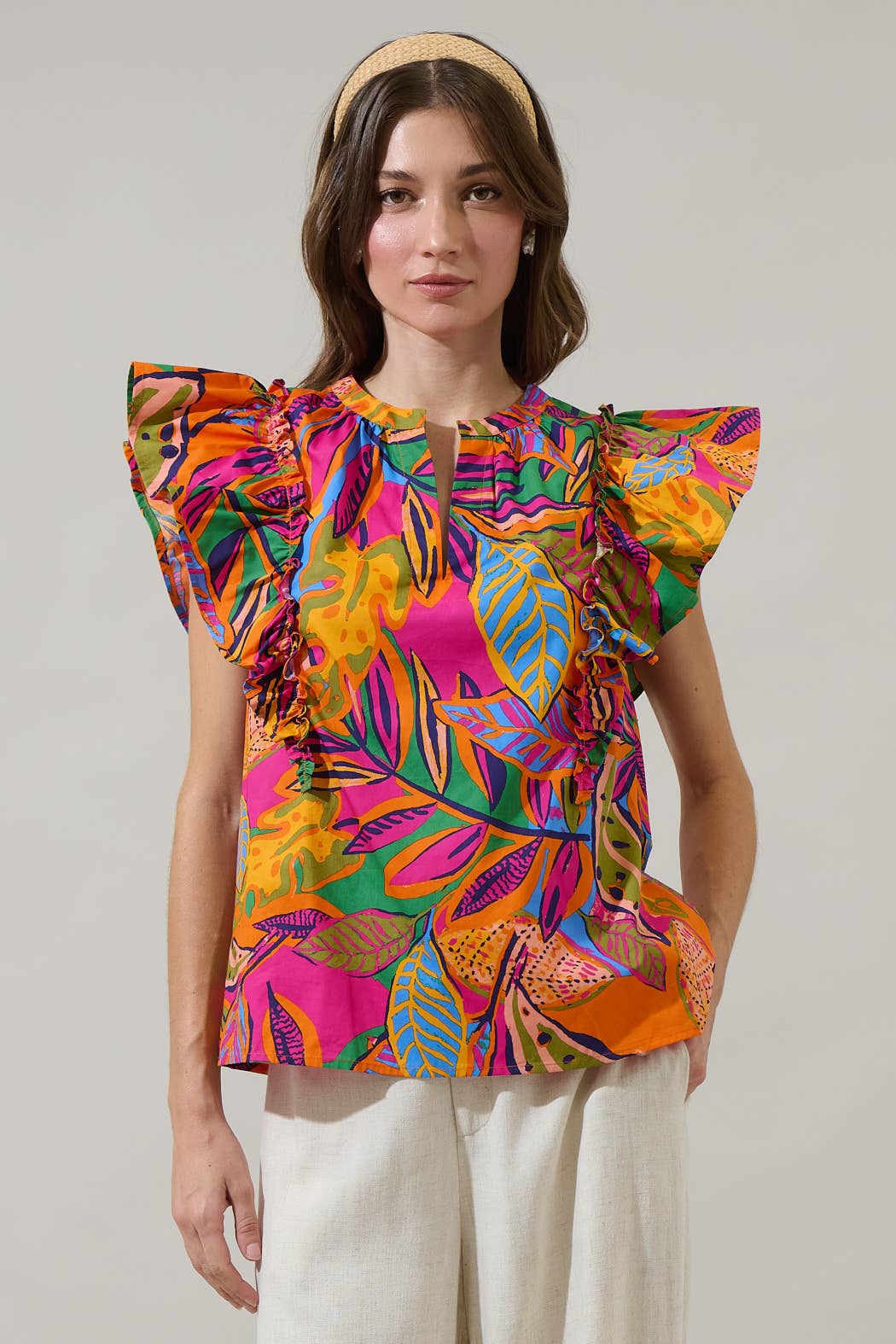 model in a multi color tropical print blouse with a white pant