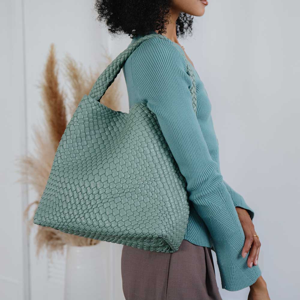 Person wearing a teal woven bag against a neutral background