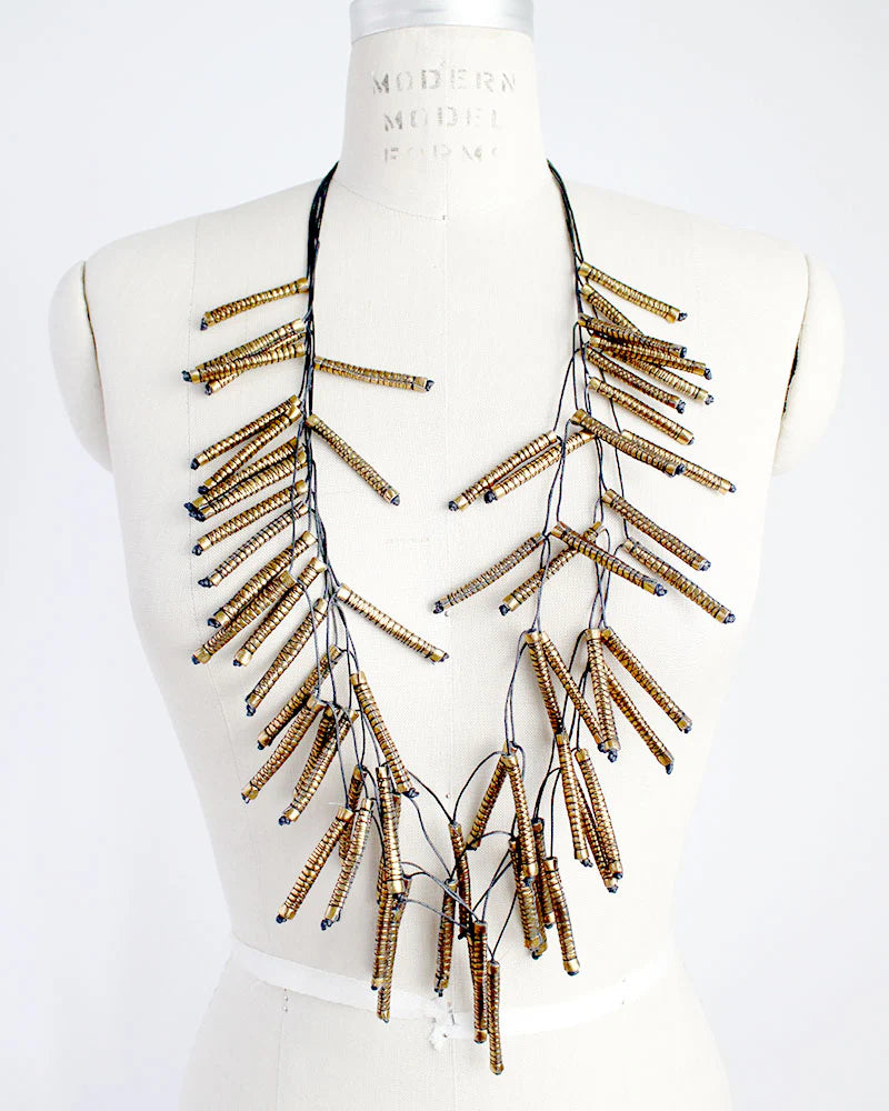 Necklace with gold and black fabric beads on a mannequin bust against a white background
