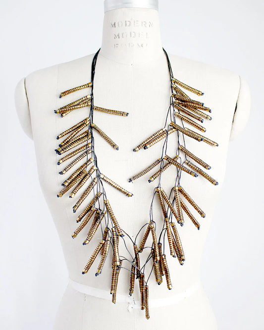 Necklace with gold and black fabric beads on a mannequin bust against a white background