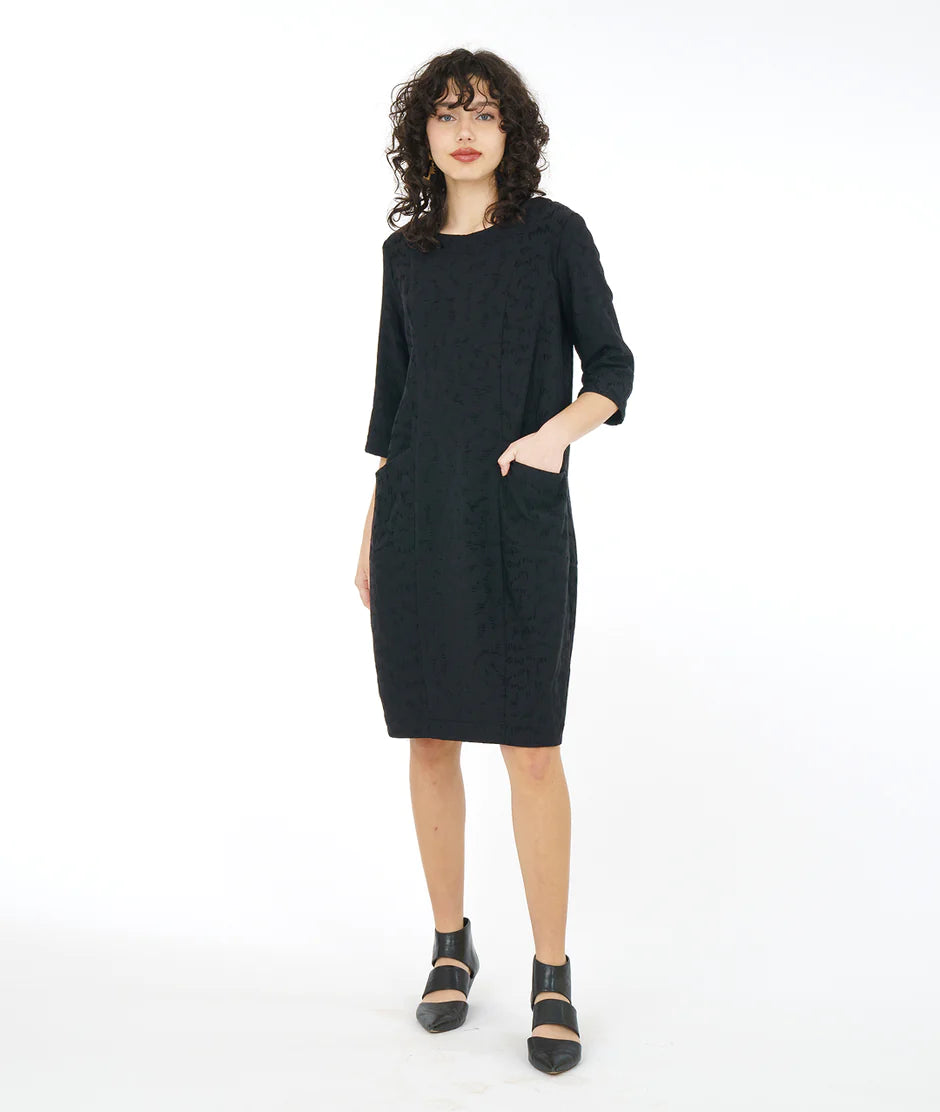 model is wearing a black loose dress with black sandals