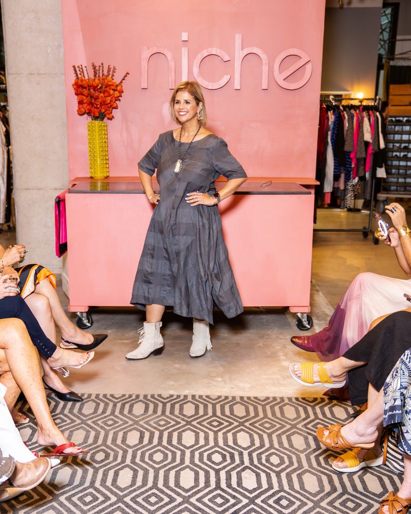 model in a dark grey patterned dress, statement earrings and boots walking down a runway