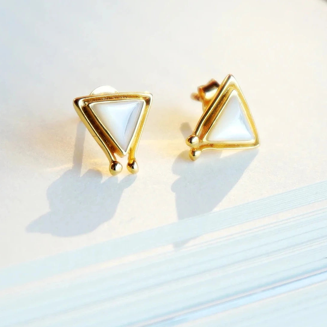Gold triangle-shaped earrings on a light background