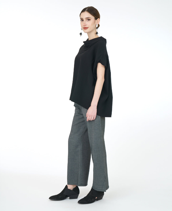 model in a wide leg grey pant with a textured black boxy top with a cowl neckline and princess seams
