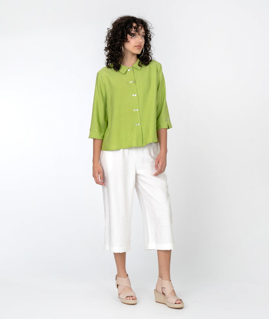 model is wearing a light green button down with white pants and heeled sandals