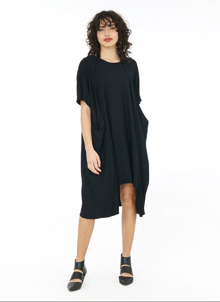 model in a black dress with a halter style strap at her neck in front of a white background
