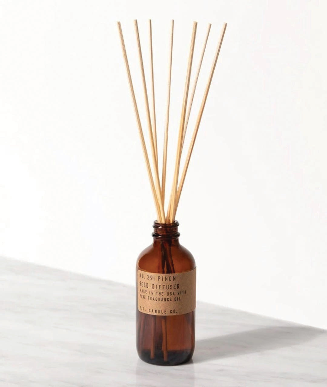 reed diffuser in a brown container with seven reed sticks coming from the top