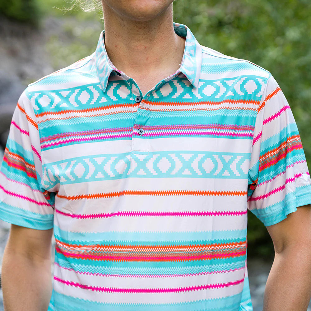 male model wearing our Serape polo. It features a Mexican serape pattern, laser engraved buttons, embroidered coyote head on the back neck, and our text logo on the left sleeve.