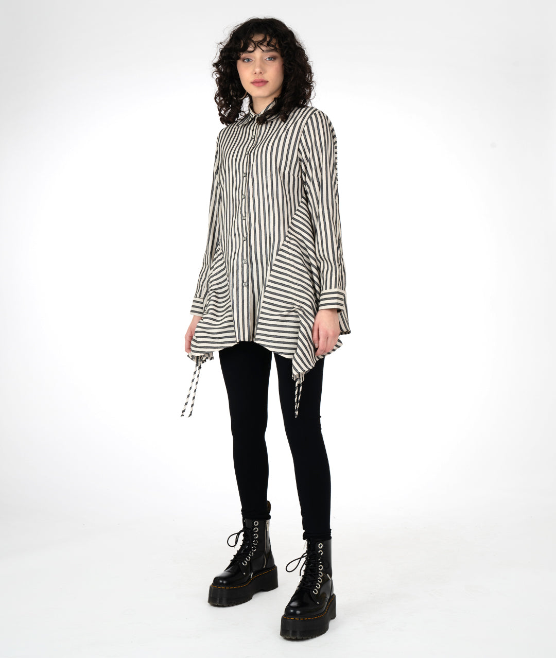 model in a black legging with a long taupe and black striped button down blouse with long sleeves and a gathered detail at either hip