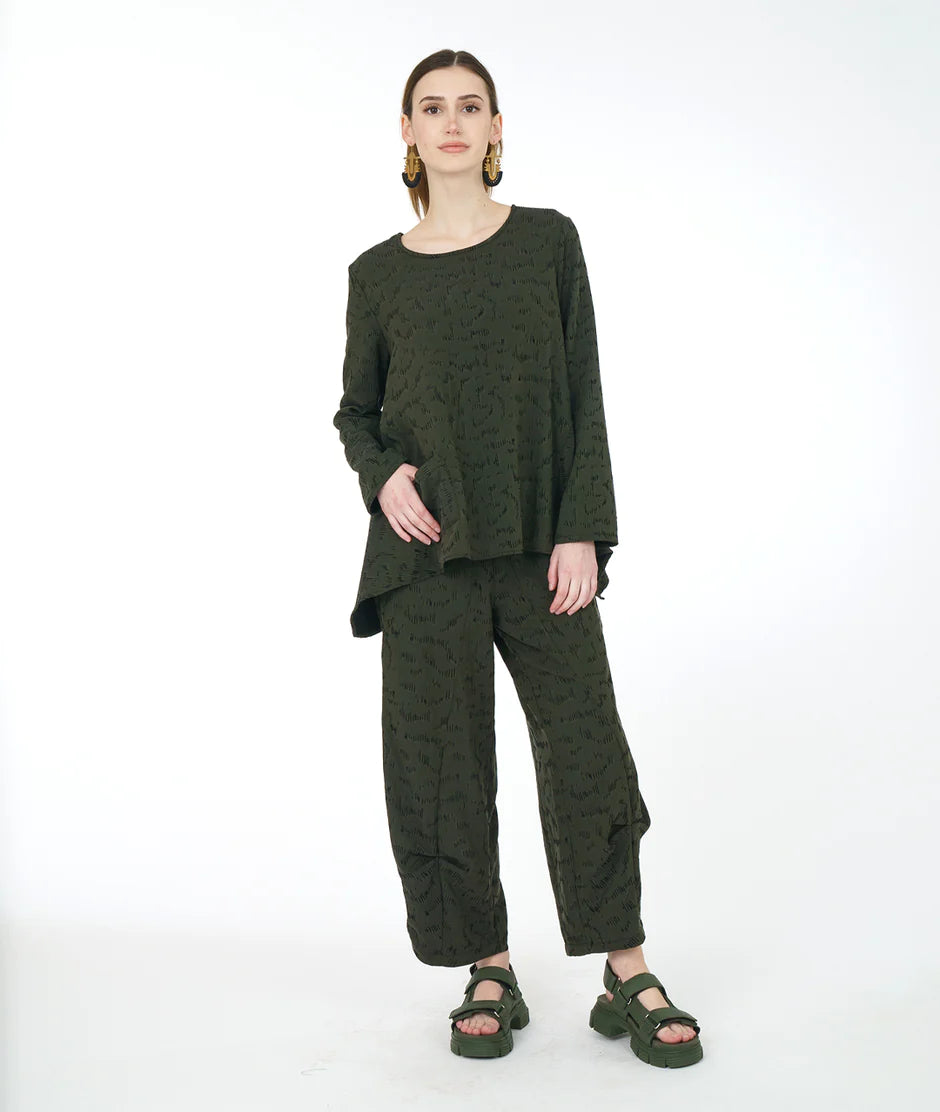 model is wearing a monochrome olive outfit against a white backdrop