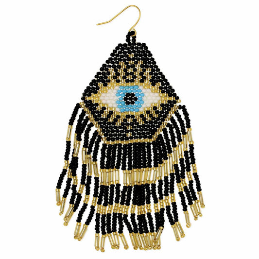 Pictured against a white background is a black and gold beaded earring with beaded fringe on the bottom. The middle of the earring features a white and blue beaded eye. There is a gold hook as the post.