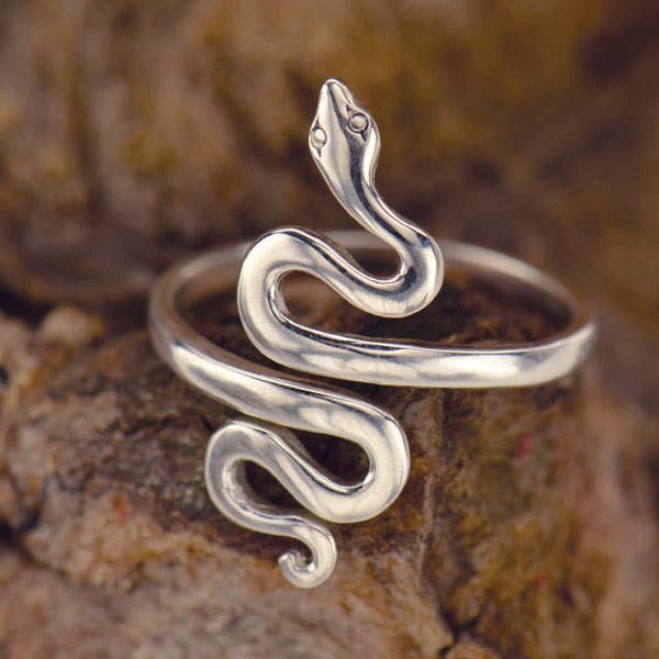 Close up of coiled snake ring in smooth silver. Ring is open in the center. Against a dark caramel texture background 