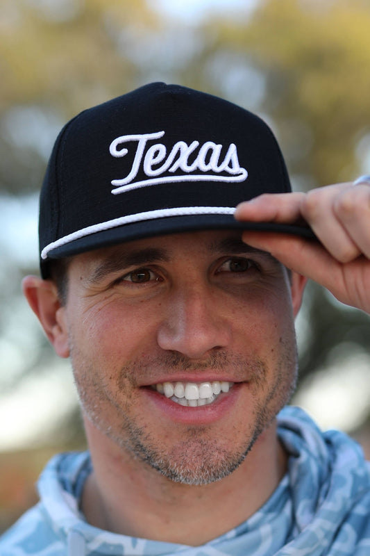 image shows a man wearing a black hat with "Texas" embroidered on it