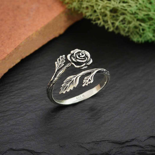 silver ring with adjustable rose design against a dark stone background