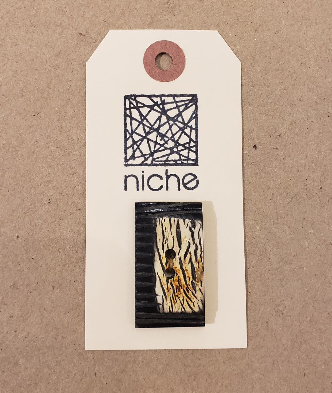 black rectangle button with tiger print on a Niche card