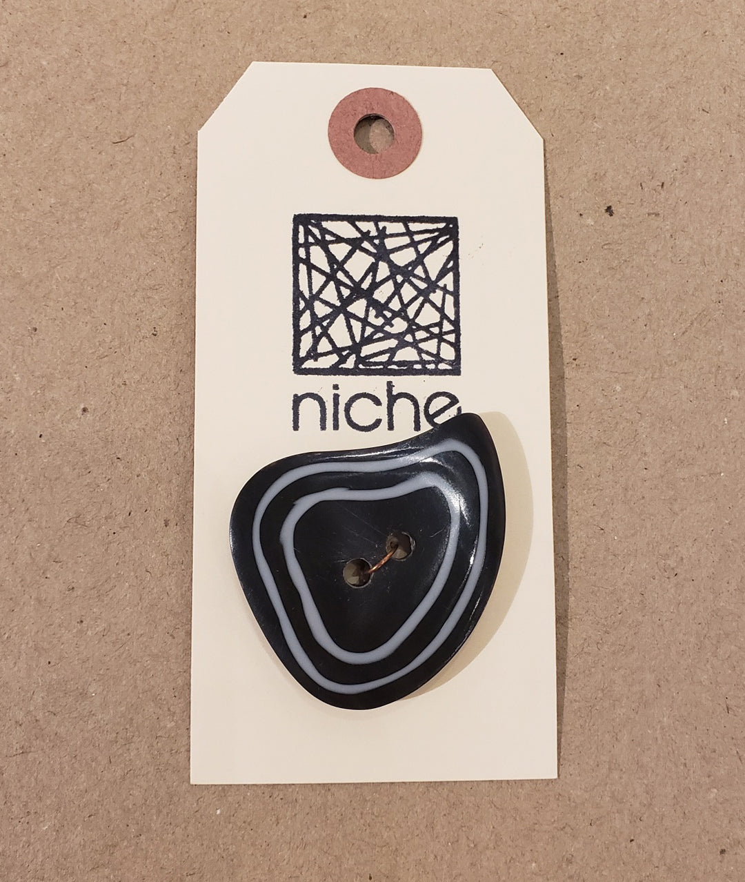 black button with white trim on a Niche card