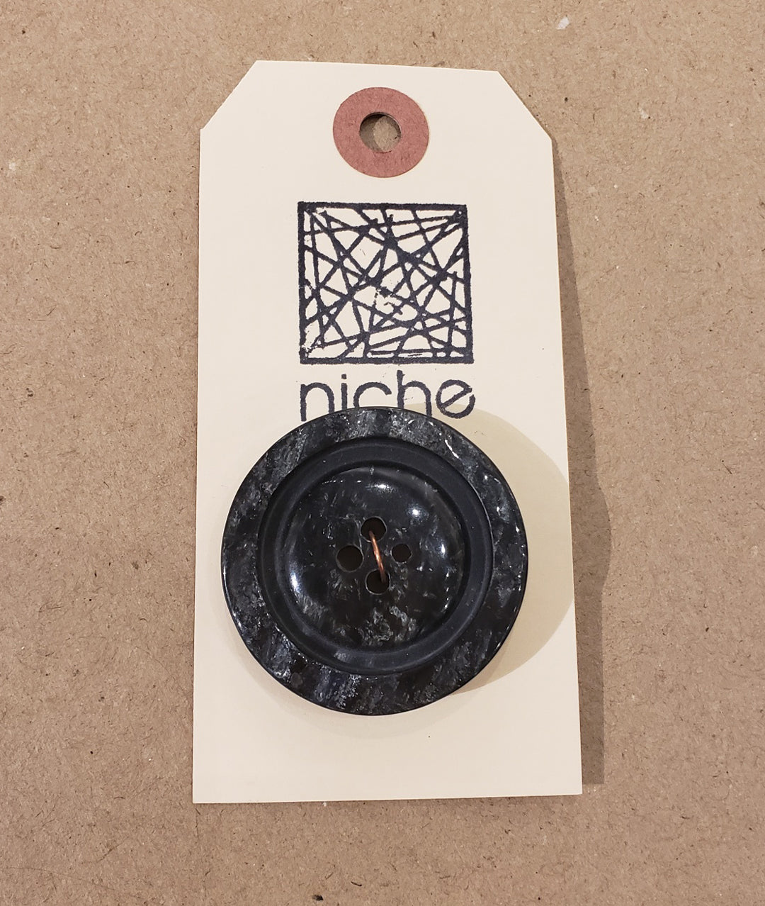 black marble button on a Niche card