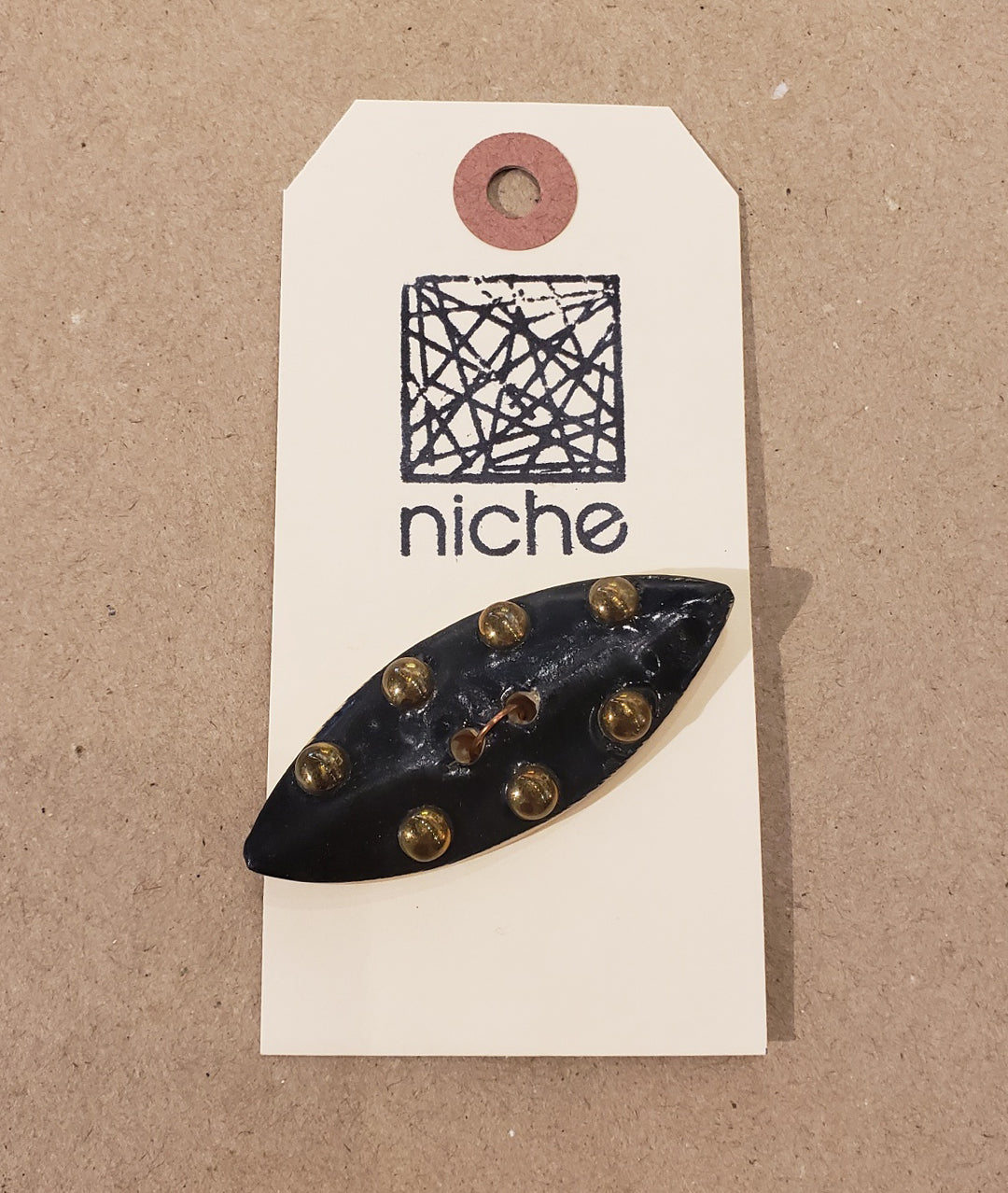 black and bronze button on a Niche card