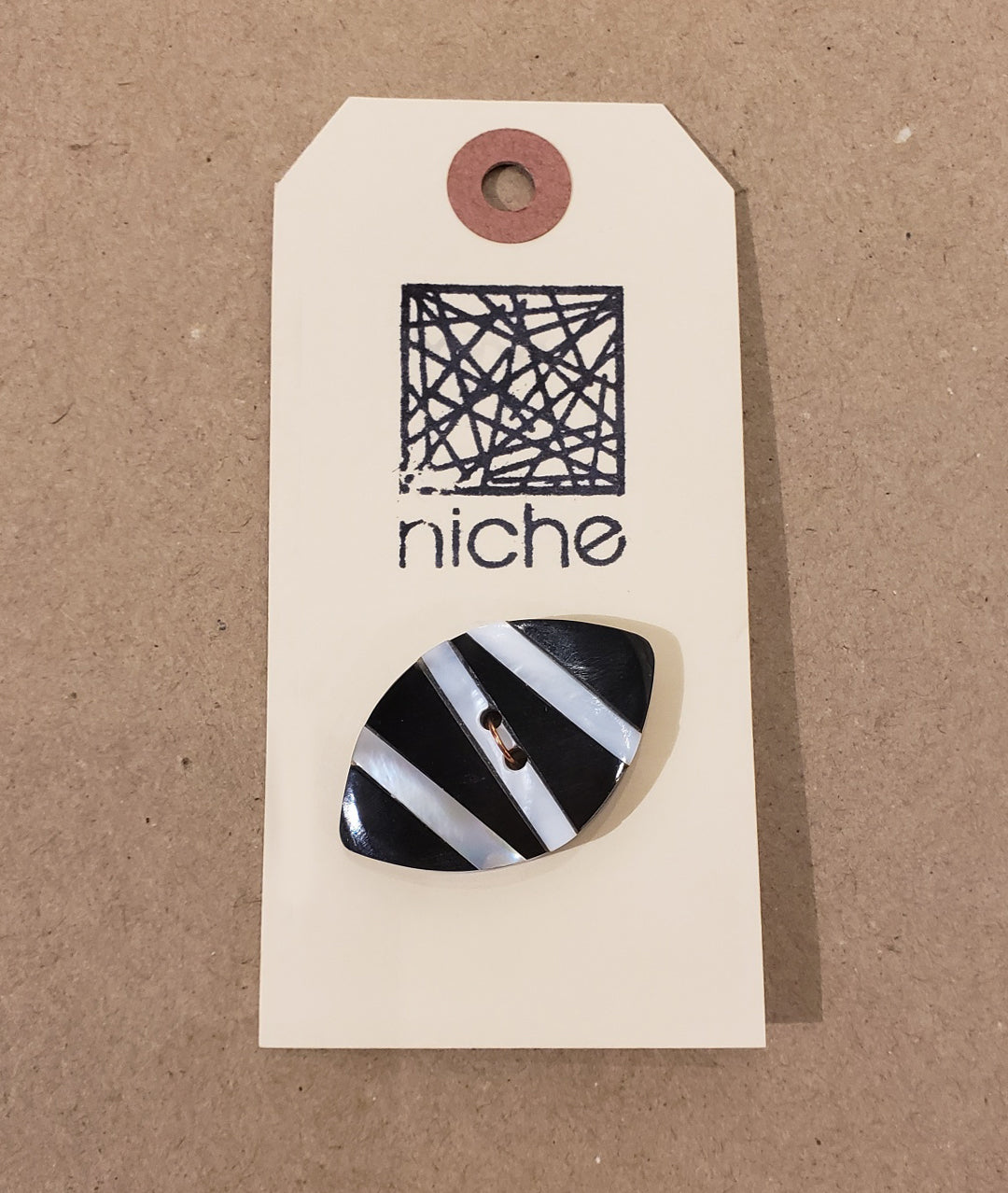 white striped button on a Niche card