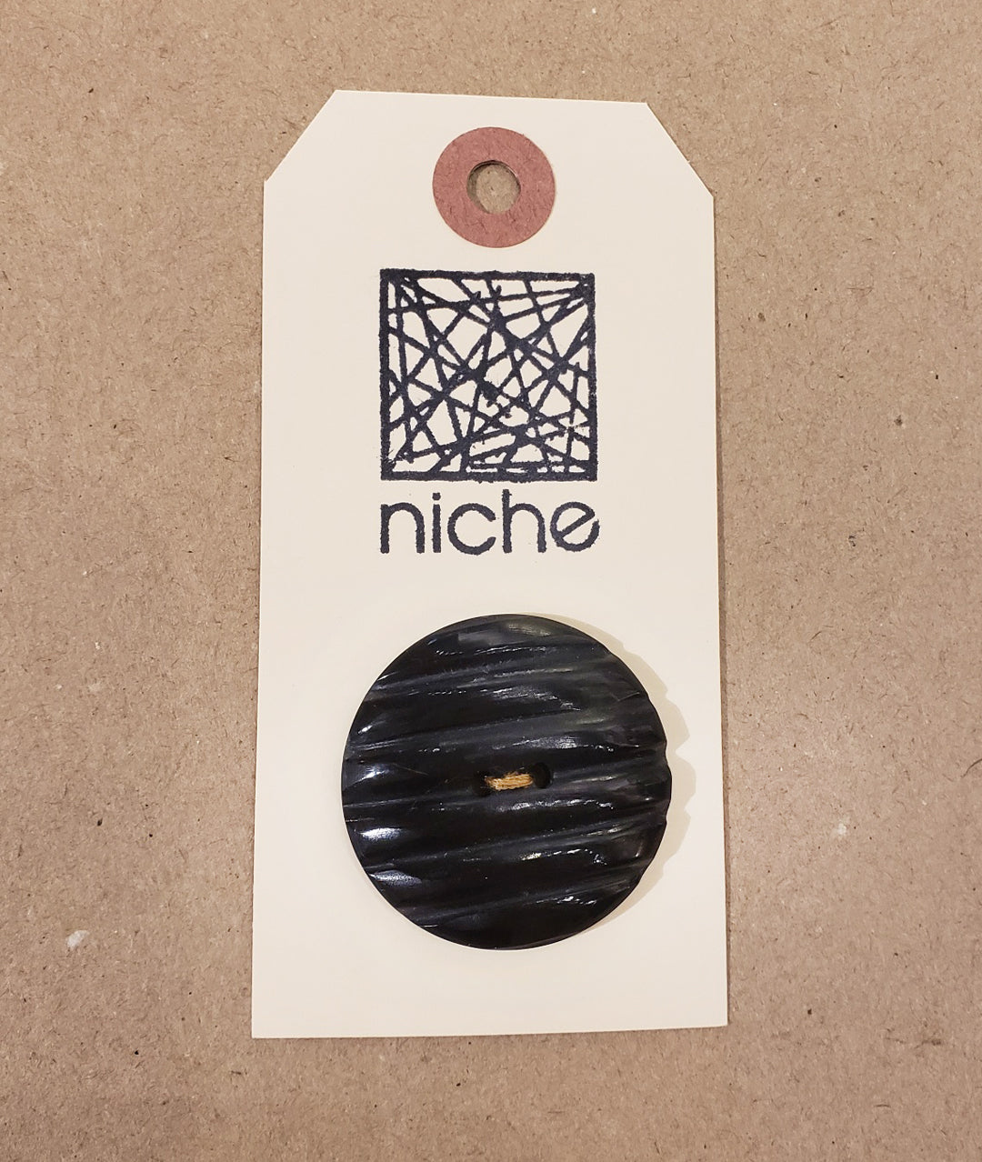 black textured button on a Niche card