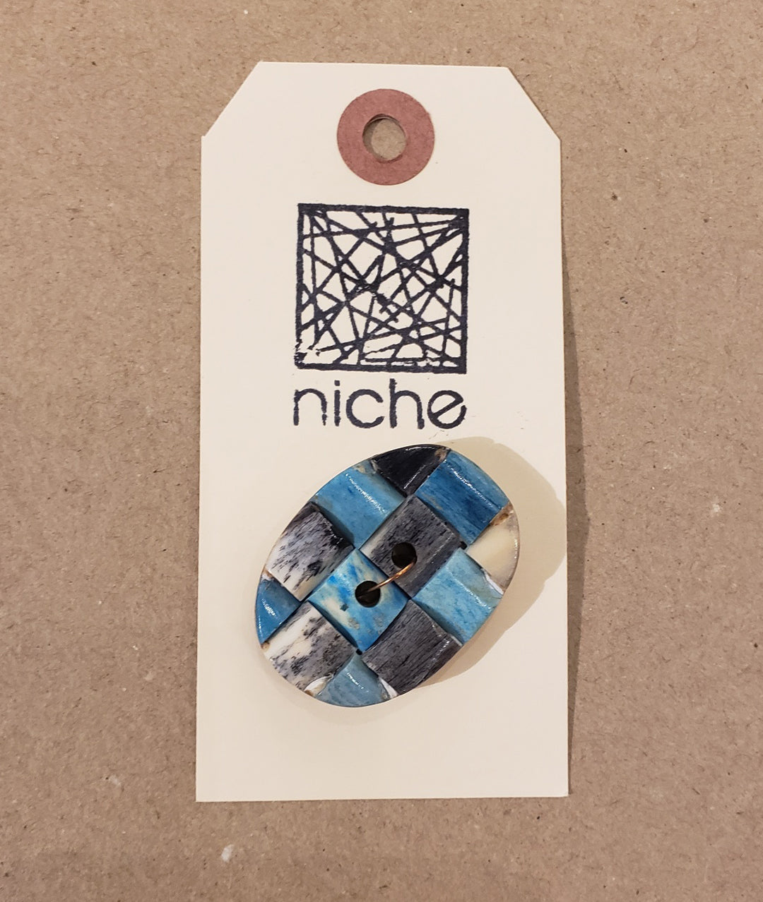 blue patchwork button on a Niche card