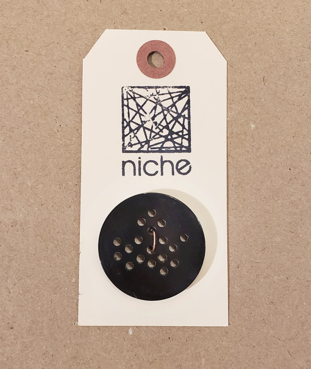 black button with holes on a Niche card