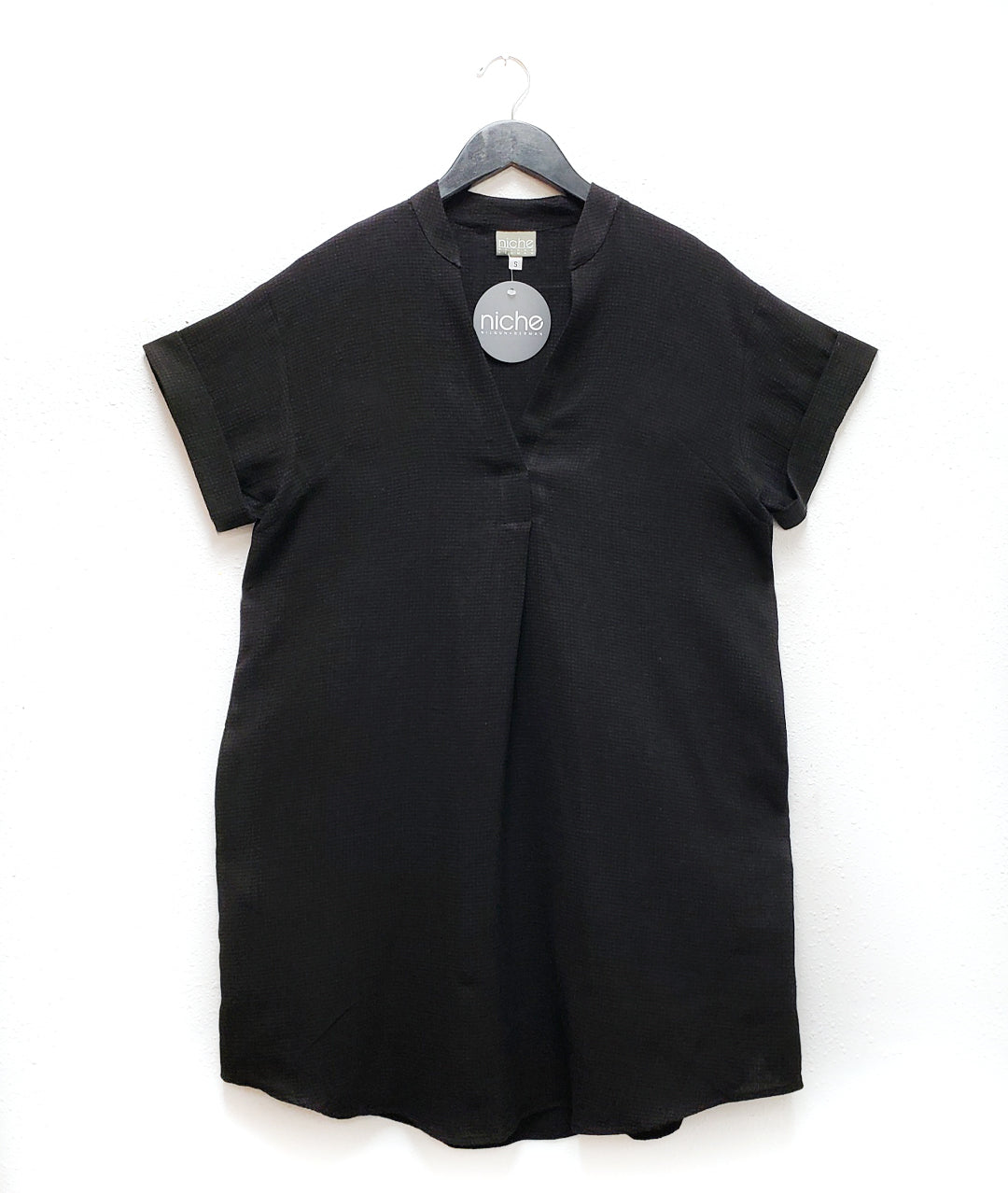 black linen dress with short cuffed sleeves, a split neckline and a boxy fit