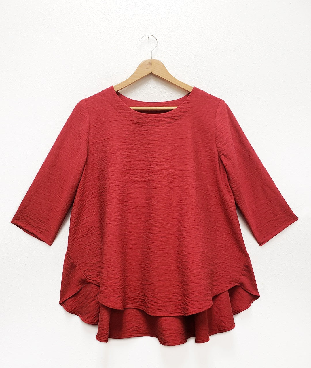 red pull over top with a full, flowy body and 3/4 sleeves