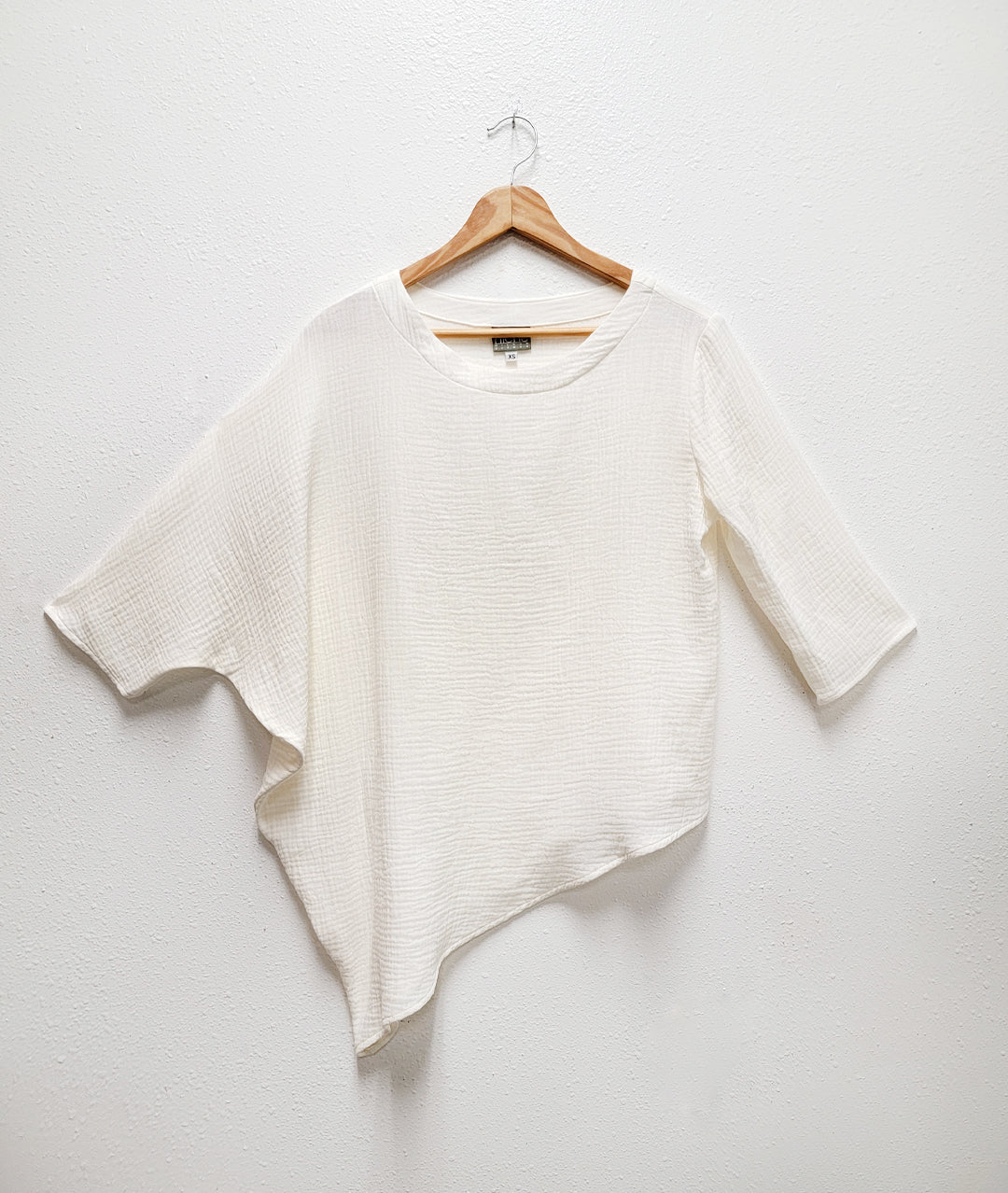 asymmetrical white top with one draped side and sleeve