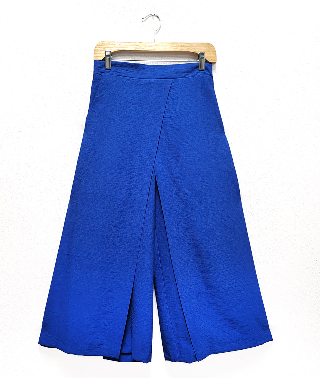 electric blue wide leg pants on a hanger with an overlapping panel in the front