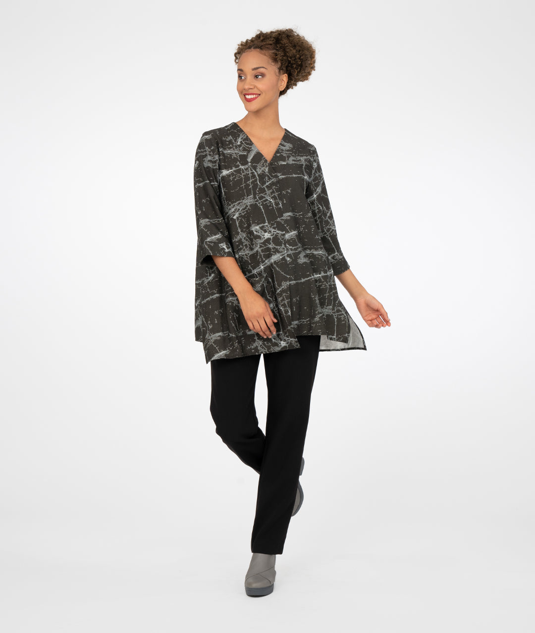 model in a slim black pant with a black marble print tunic with a vneckline, 3/4 sleeves an uneven hemline and a single square pocket on the hip