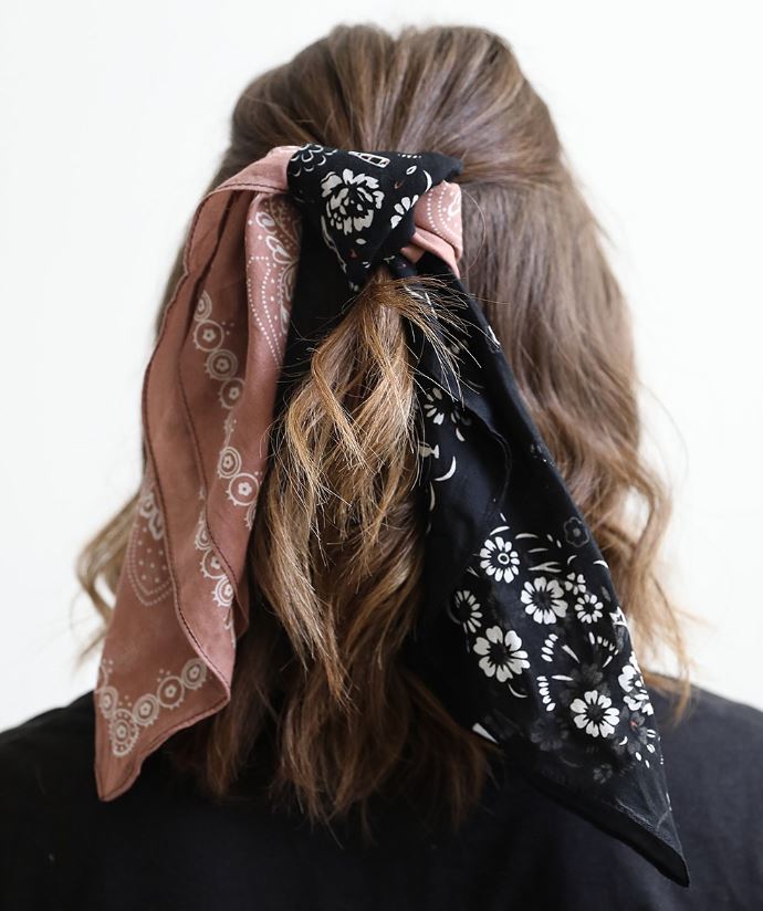 Pictured is the back of a brunette model's head. The photo features the two toned bandana tied around the model's hair in a half ponytail.