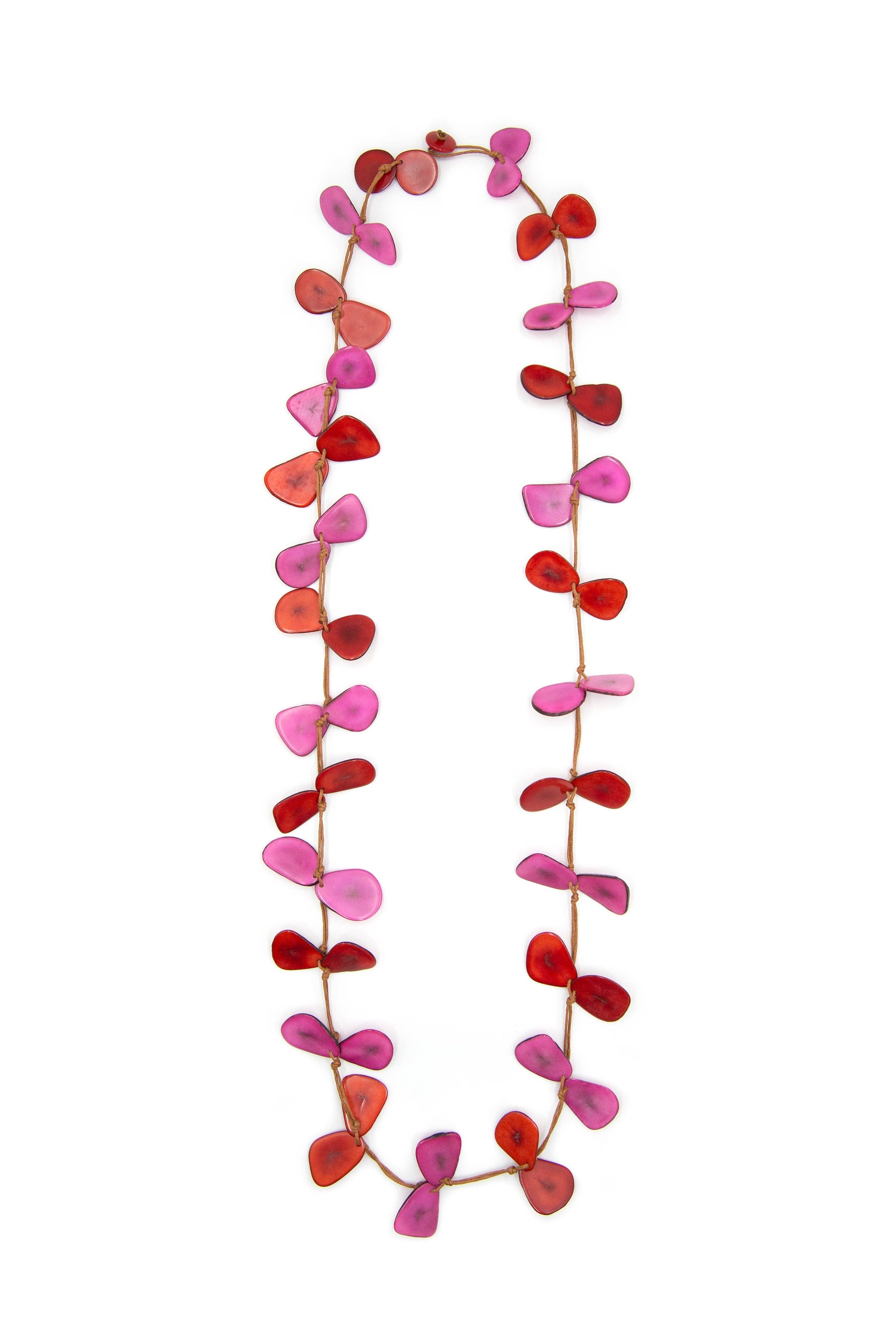 Close up of necklace made of cord and dyed slices of tagua nut against a white background. Necklace is red and dark pink