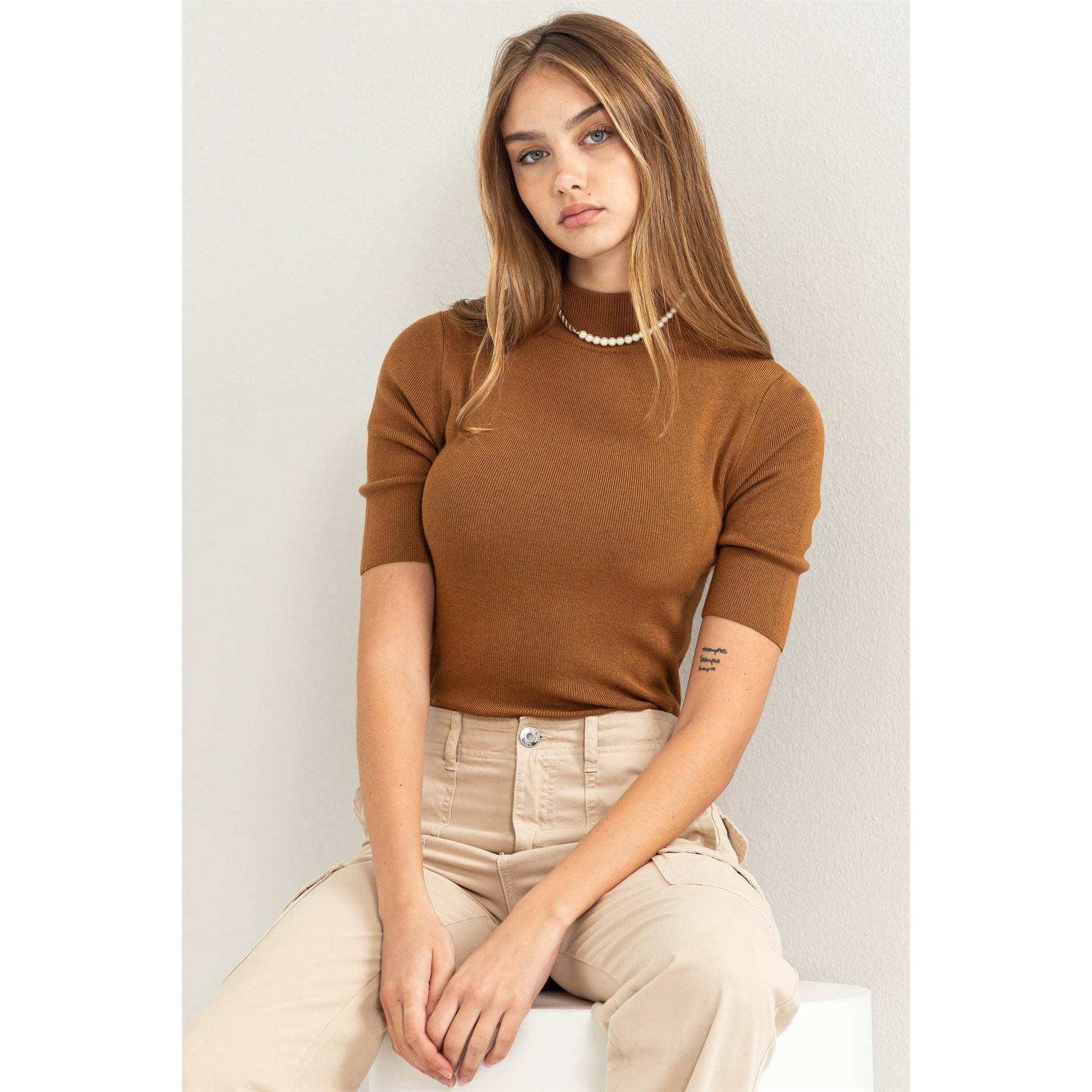 model is wearing a brown mock neck short sleeve tee with light colored pants