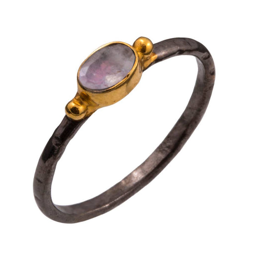 Faceted rainbow moonstone oval in vermeil bezel on dark rhodium band ring against a white background