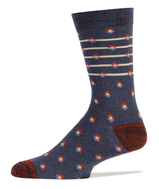 Pictured against a white background are navy blue men's crew socks. They feature red around the toe and heel and have white stripes at the top of the sock with white and blue colored diamonds throughout.