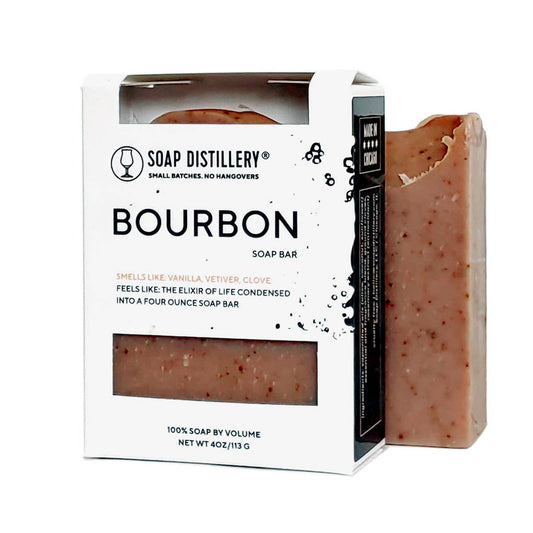 Photo of a brown speckled  bar of soap next to a packaged bar of soap in a black and white box with a label that says "Bourbon" with a description.