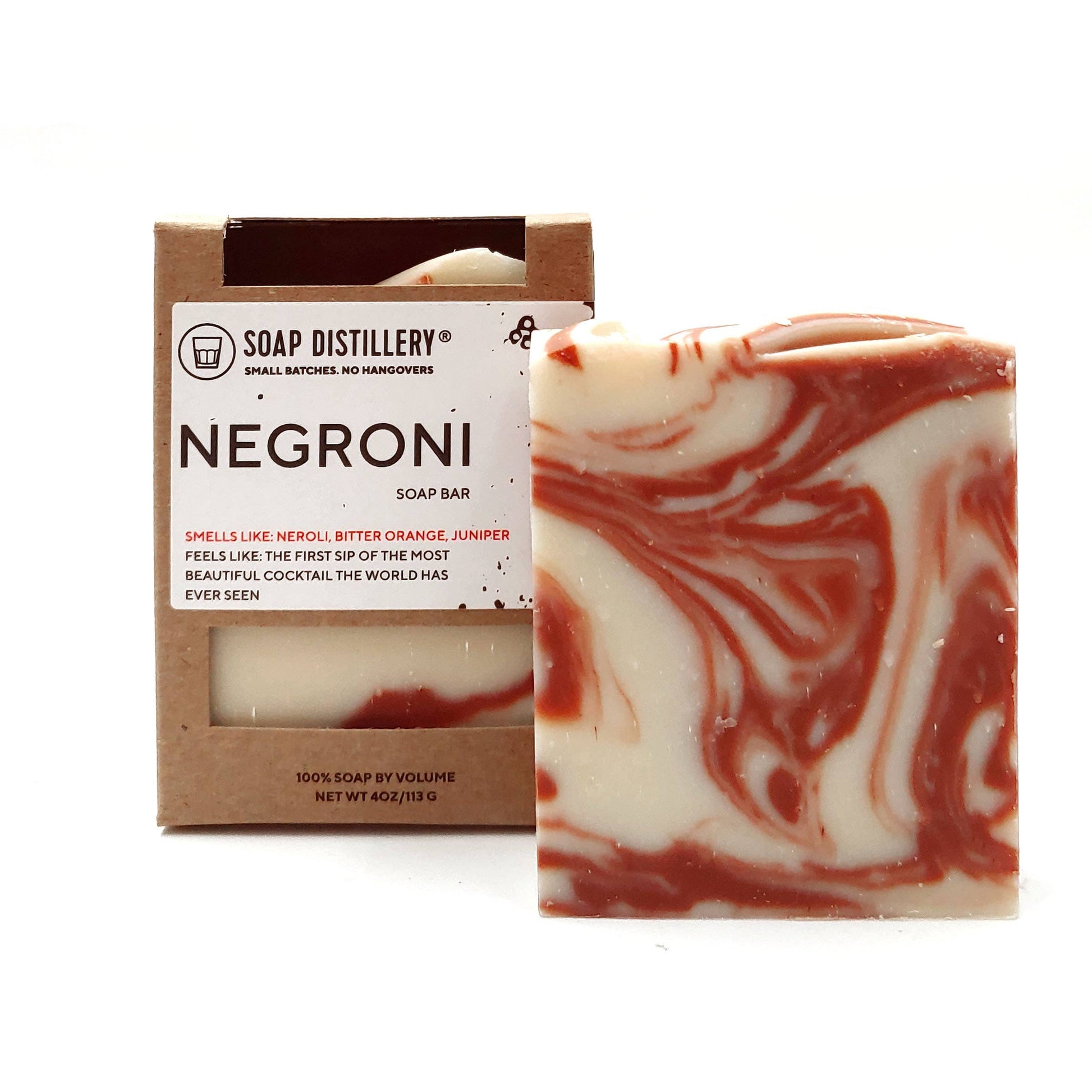 Photo of orange and cream marbeled bar of soap next to a packaged bar of soap in a brown box with a label that says "Negroni" with a description.