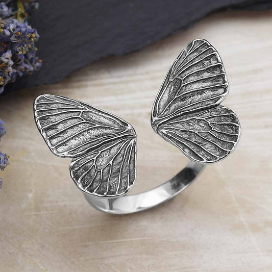 silver butterfly wings ring against a wooden background
