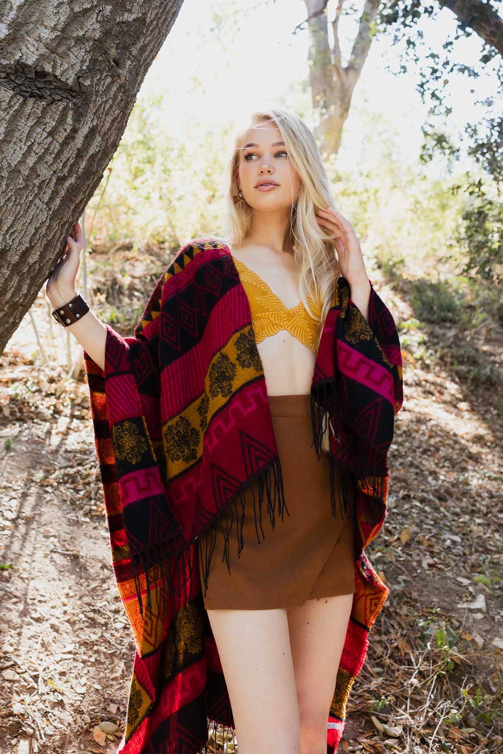 model is pictured outdoors wearing an Aztec-printed poncho