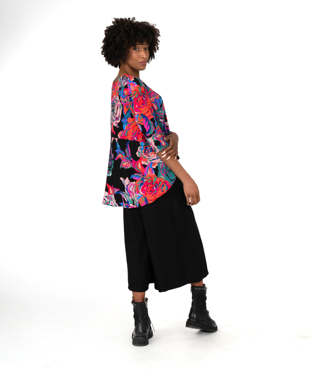 model in a straight leg black pant with a floral print blouse in a high low hem