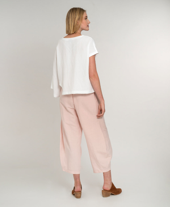 back view model in a blush pink pant with detailing at the hem, worn with an asymmetrical white top