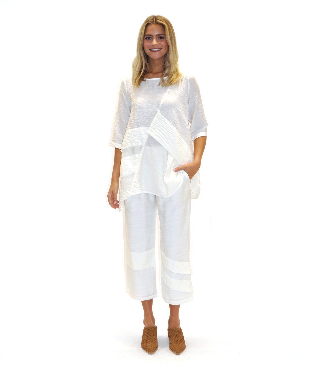 model in a white top and bottom with decorative pleating across the body and pant legs