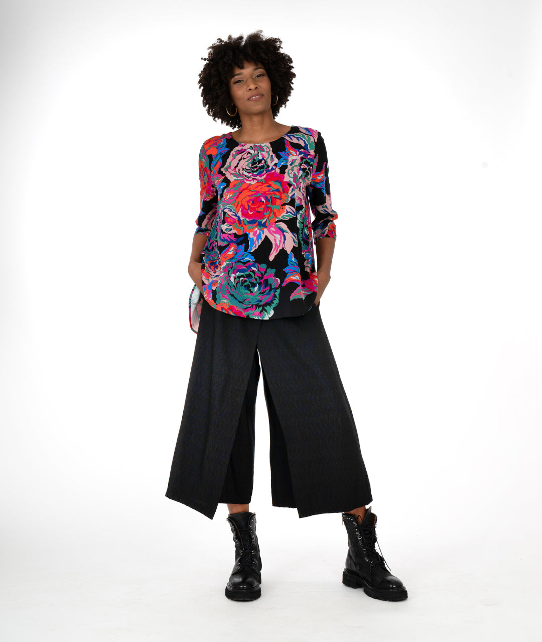 model in a straight leg black pant with a floral print blouse in a high low hem