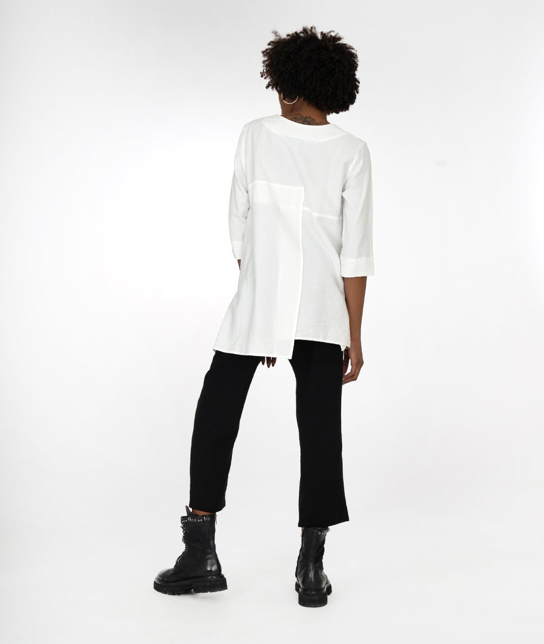 model in a slim black pant, with a white pull over top with 3/4 sleeves, a vneck, asymmetrical hem line and single squared hip pocket