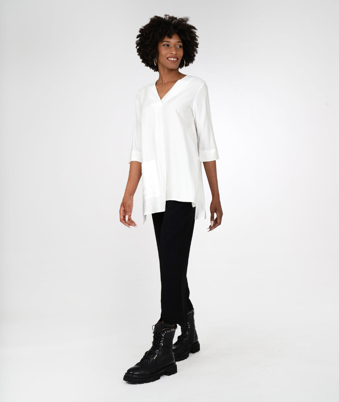 model in a slim black pant, with a white pull over top with 3/4 sleeves, a vneck, asymmetrical hem line and single squared hip pocket