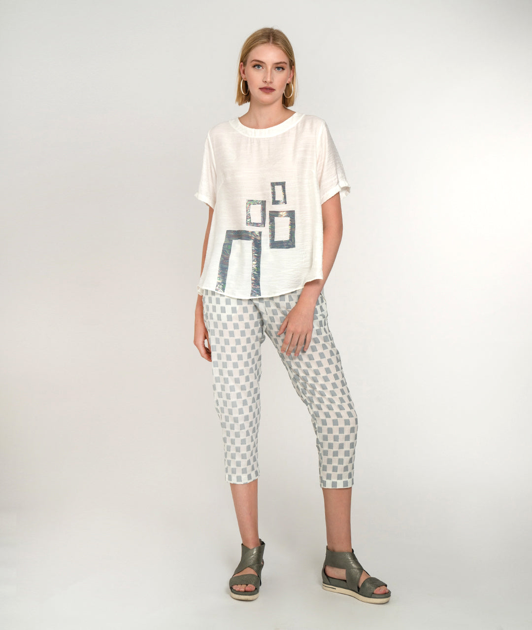 model in a white tee with a grey and white checker crop pant
