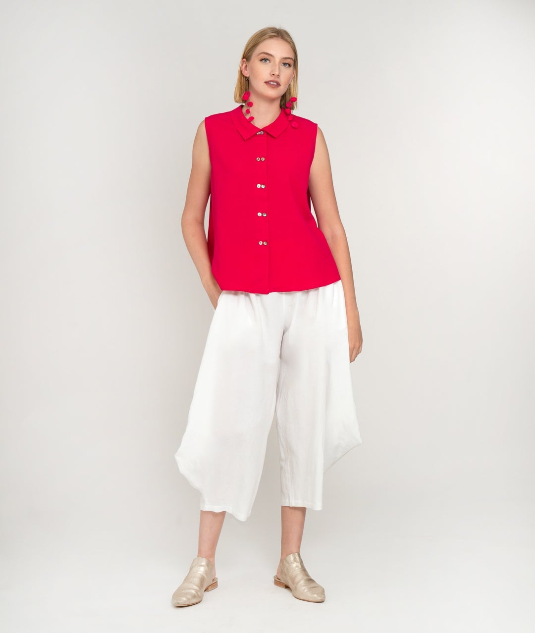 model in a wide leg white pant with a raspberry pink sleeveless button up blouse